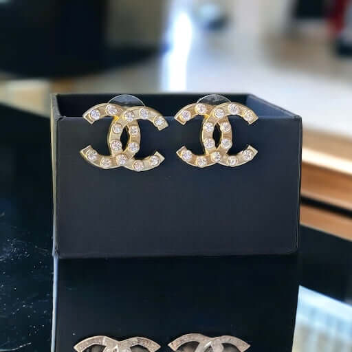 Chanel Gold Double C with raised clear Crystals Post EarringsThese Chanel Gold Double C earrings feature a rare design with clean style and a rock star appeal. The raised clear crystals add a touch of sparkle to these chic accessories. Crafted with gold, My Mama Found What