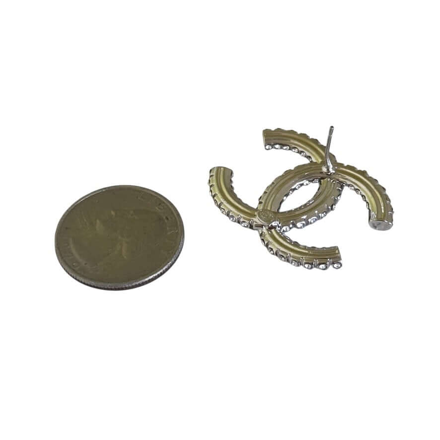 Chanel Silver CC Big Earrings next to a coin, showcasing crystal-encrusted design in like-new pre-owned condition.