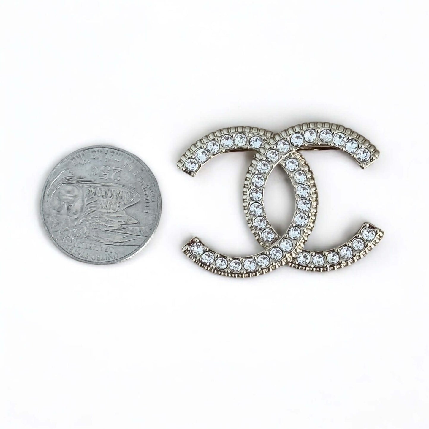Pre-owned Chanel lighter brooch with CC design and crystals, alongside a quarter for size reference. My Mama Found What