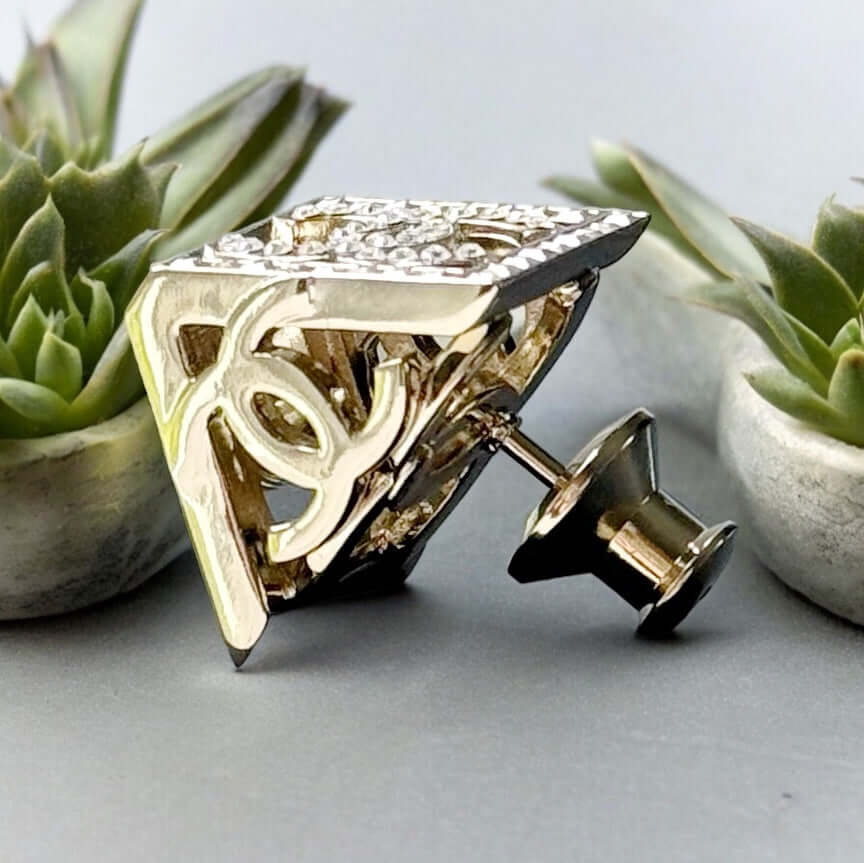 Chanel Lighter Gold Double C with Crystals Triangle Styled Smaller Brooch PinSet your style on fire with the Chanel Lighter Gold Double C brooch pin. Covered in dazzling crystals, this triangular piece adds a touch of bling to any outfit. Playfully chic,
