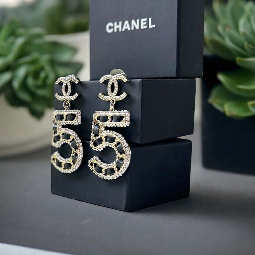 Chanel Gold Number 5 Big Dangle CC EarringsMake a statement with these iconic Chanel Gold Number 5 Big Dangle CC Earrings. The perfect addition to any outfit, these trendy and luxurious earrings feature gold plating, clear crystals, and a bold Chanel No.