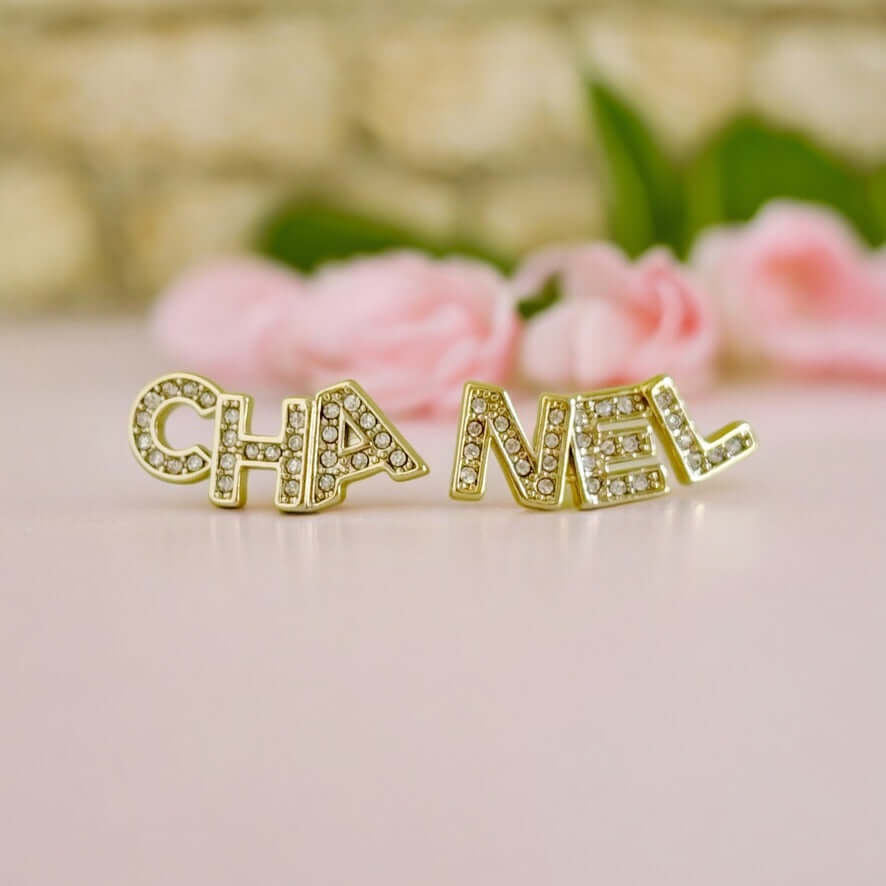 Chanel 14K Gold Name Cut-Out w/ clear crystals earringsAdd a touch of elegance and playfulness to your outfit with these Chanel 14K Gold Cut-Out Name earrings. The clear crystals add a subtle sparkle, making them perfect for any occasion. Their smaller si