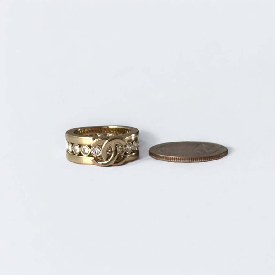 CHANEL CC Gold ring with crystals, pre-owned, displayed next to a coin for size comparison, in excellent condition.