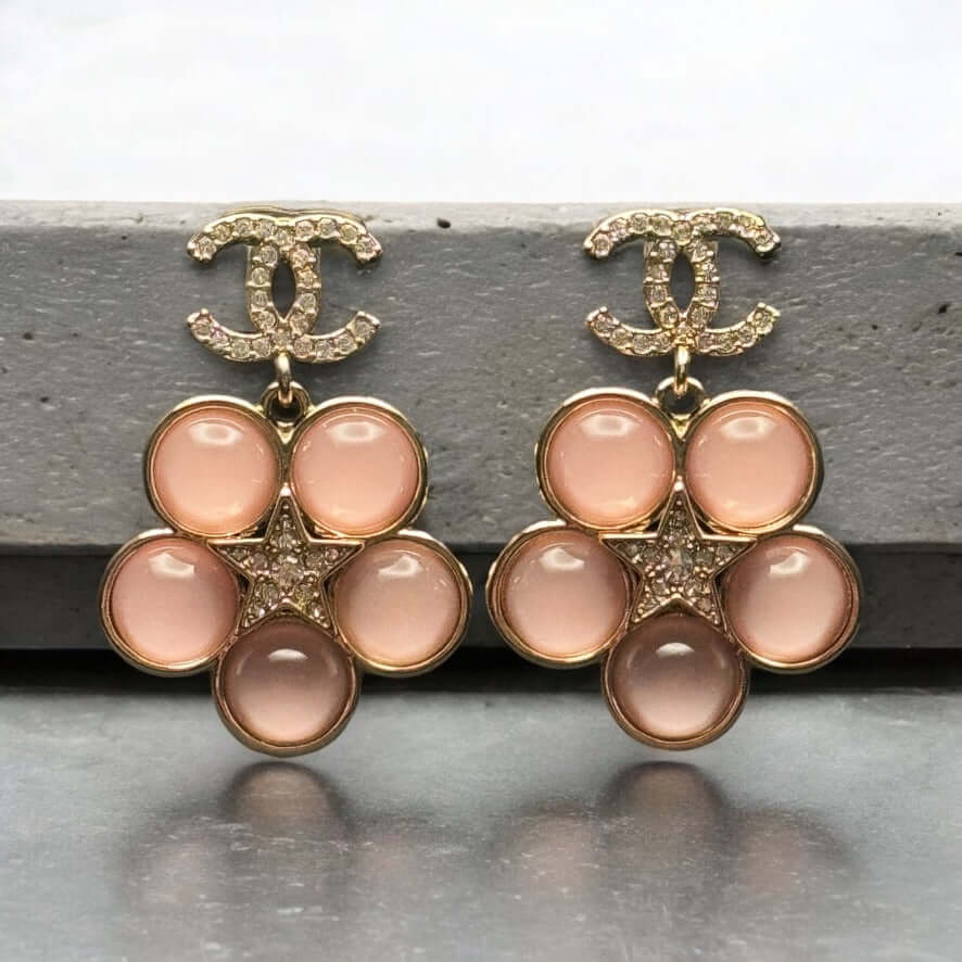 Authentic CHANEL CC Lighter Pink Dangle Earrings with Gold Stars in excellent pre-owned condition.