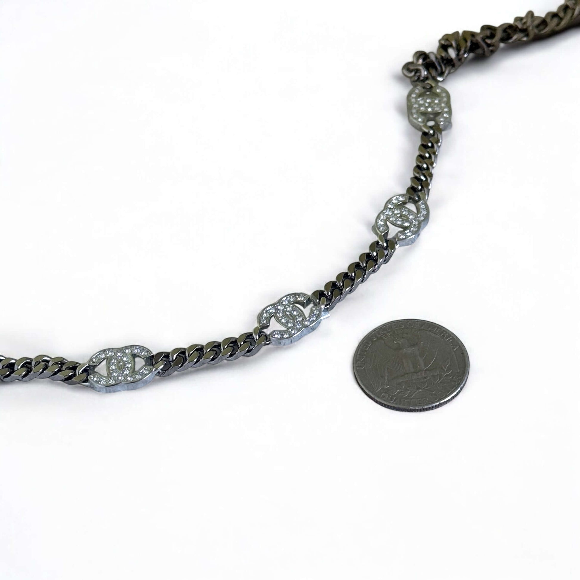 Authentic Chanel CC Choker in gunmetal, crystal-encrusted CCs, adjustable design, with a quarter for size reference.