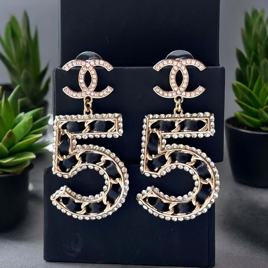 Chanel Gold Number 5 Big Dangle CC EarringsMake a statement with these iconic Chanel Gold Number 5 Big Dangle CC Earrings. The perfect addition to any outfit, these trendy and luxurious earrings feature gold plating, clear crystals, and a bold Chanel No.