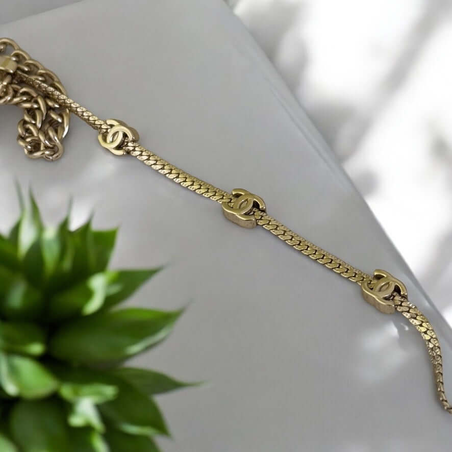 Authentic Chanel CC Gold Plated Chain necklace with mini CC details and adjustable length, displayed with greenery.