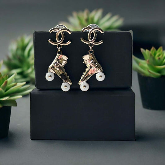 Chanel 14K Gold Tone Double C RARE Funky Rollar Skates Dangling EarringsRARE Hard To Find Unleash your fierce inner rockstar with these rare Chanel 14K Gold Tone Double C Dangling Earrings! Plated in 14k gold, the funky rollar skates with white enamel whe