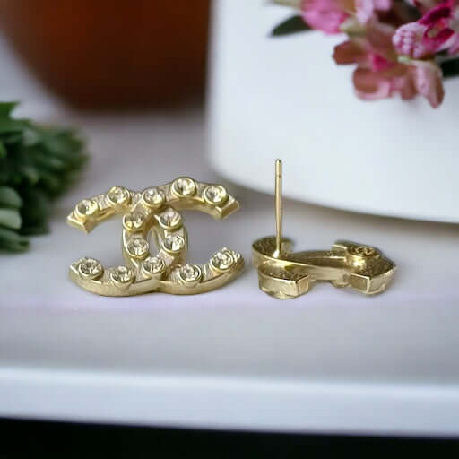 Chanel Gold Double C with raised clear Crystals Post EarringsThese Chanel Gold Double C earrings feature a rare design with clean style and a rock star appeal. The raised clear crystals add a touch of sparkle to these chic accessories. Crafted with gold,