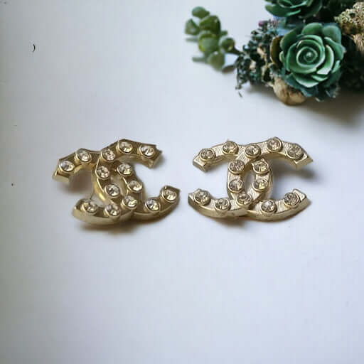 Chanel Gold Double C with raised clear Crystals Post EarringsThese Chanel Gold Double C earrings feature a rare design with clean style and a rock star appeal. The raised clear crystals add a touch of sparkle to these chic accessories. Crafted with gold,