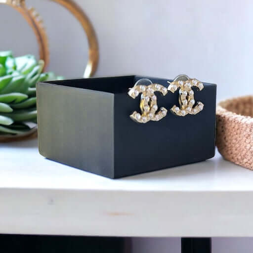 Chanel Gold Double C with raised clear Crystals Post EarringsThese Chanel Gold Double C earrings feature a rare design with clean style and a rock star appeal. The raised clear crystals add a touch of sparkle to these chic accessories. Crafted with gold,