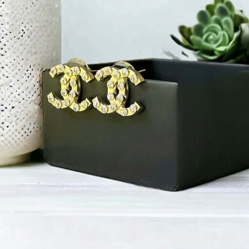 Chanel Gold Double C with raised clear Crystals Post EarringsThese Chanel Gold Double C earrings feature a rare design with clean style and a rock star appeal. The raised clear crystals add a touch of sparkle to these chic accessories. Crafted with gold,