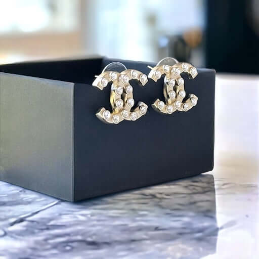 Chanel Gold Double C with raised clear Crystals Post EarringsThese Chanel Gold Double C earrings feature a rare design with clean style and a rock star appeal. The raised clear crystals add a touch of sparkle to these chic accessories. Crafted with gold,