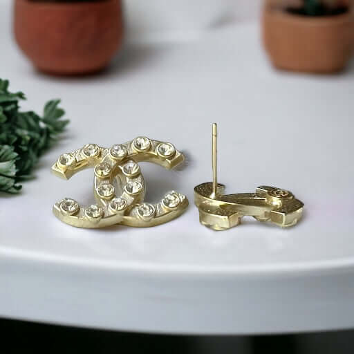 Chanel Gold Double C with raised clear Crystals Post EarringsThese Chanel Gold Double C earrings feature a rare design with clean style and a rock star appeal. The raised clear crystals add a touch of sparkle to these chic accessories. Crafted with gold, My Mama Found What 