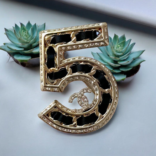 Chanel Gold Number 5 with Double C, Black Leather & CrystalsExperience the height of luxury and chic with this Chanel Gold Number 5 with Double C, Black Leather & Crystals. Inspired by the iconic Number 5 perfume symbol, this rare and like-new bag showcas My Mama Found What 