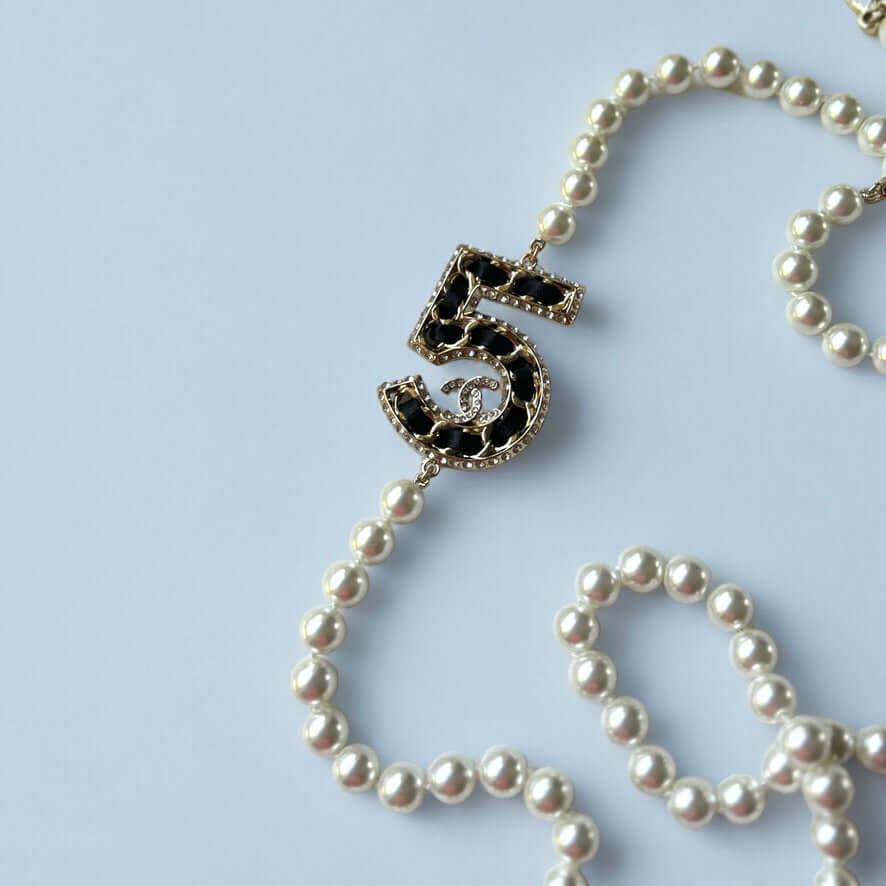 Chanel Knotted Pearl No.5 CC Sweater NecklaceIndulge in this gorgeous necklace adorned with a hand knotted pearl, Number 5 Chanel perfume charm, and sparkling crystals. The playful CC logo adds a touch of gold to the elegant black leather. Perfect for add My Mama Found What 