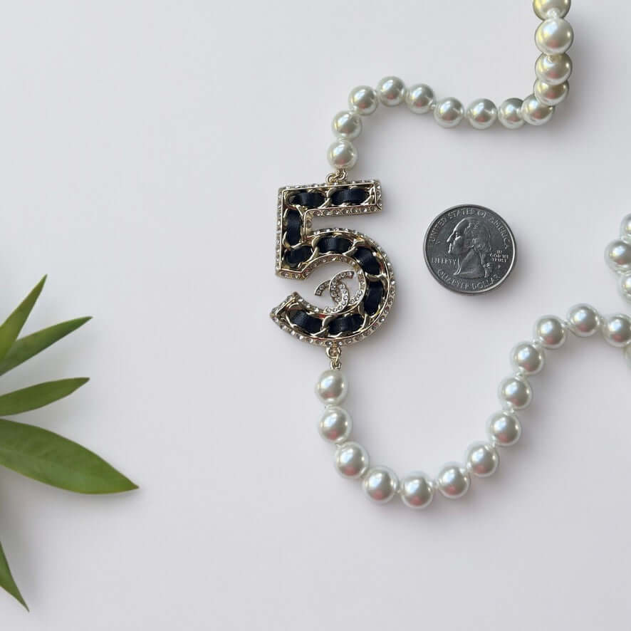 Chanel Knotted Pearl No.5 CC Sweater NecklaceIndulge in this gorgeous necklace adorned with a hand knotted pearl, Number 5 Chanel perfume charm, and sparkling crystals. The playful CC logo adds a touch of gold to the elegant black leather. Perfect for add My Mama Found What 