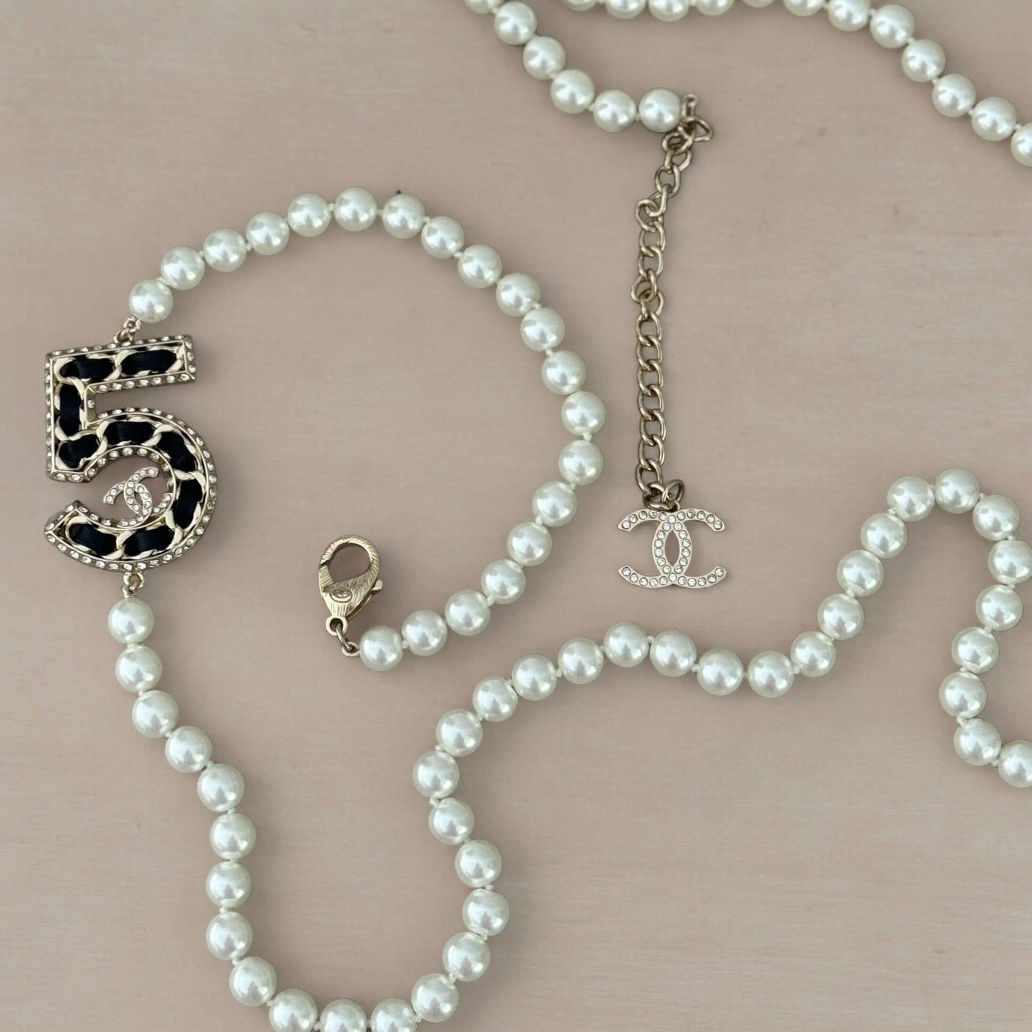 Chanel Knotted Pearl No.5 CC Sweater NecklaceIndulge in this gorgeous necklace adorned with a hand knotted pearl, Number 5 Chanel perfume charm, and sparkling crystals. The playful CC logo adds a touch of gold to the elegant black leather. Perfect for add My Mama Found What 