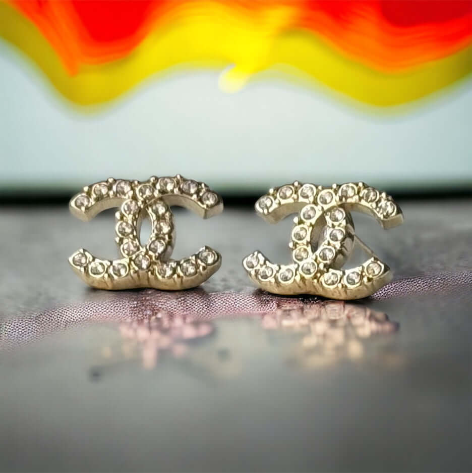 Chanel Lighter Gold Smaller Double C with round clear crystals earringsAccessorize with these lightweight Chanel Gold Double C earrings, featuring clear round crystals that add subtle sparkle to any outfit. Versatile for any occasion, these elegant earrin