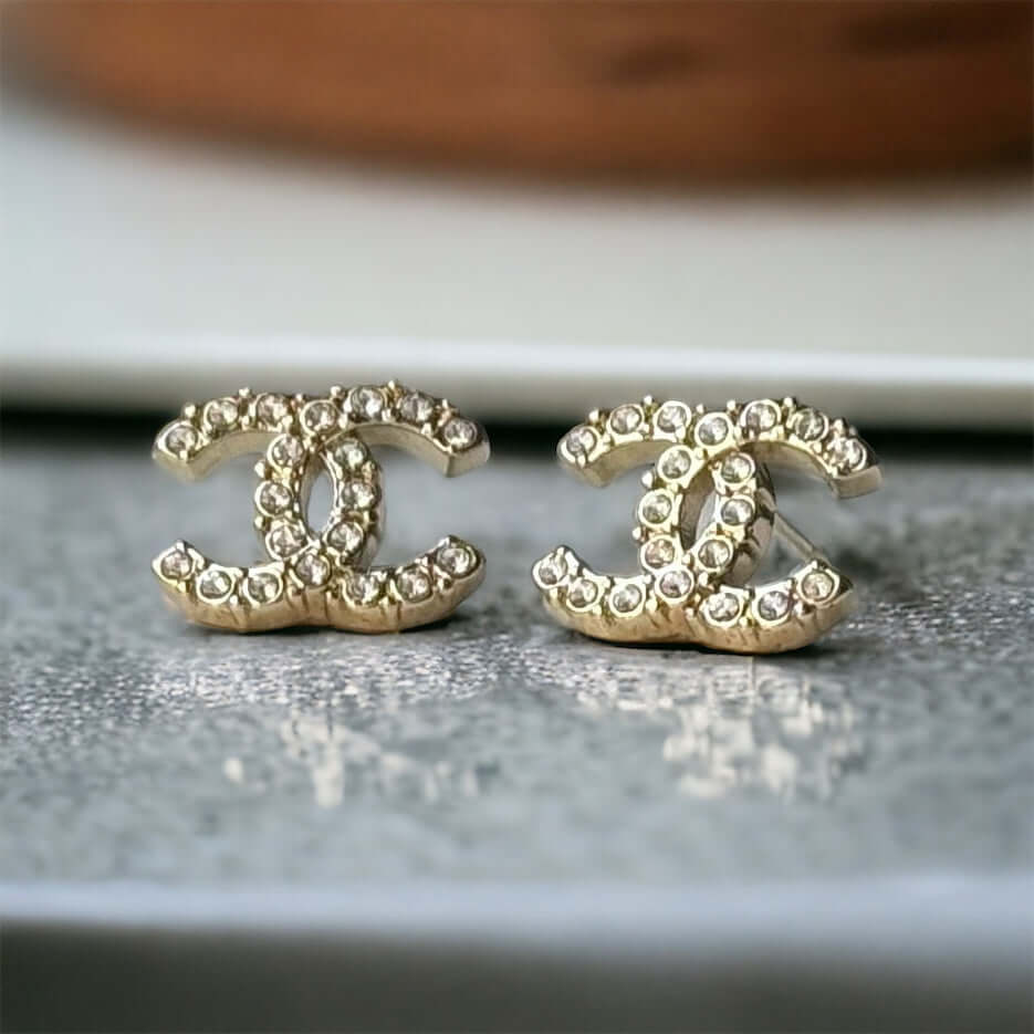 Chanel Lighter Gold Smaller Double C with round clear crystals earringsAccessorize with these lightweight Chanel Gold Double C earrings, featuring clear round crystals that add subtle sparkle to any outfit. Versatile for any occasion, these elegant earrin