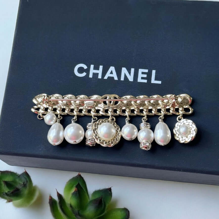 Chanel Rare Lighter Gold Long with Various Dangling Charms Brooch Pin 21 PIntroducing an elegant and rare brooch from Chanel, the Rare Lighter Gold Long Brooch with Various Dangling Charms! Accented with faux pearls and crystals, this brooch features a mi