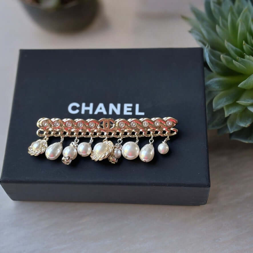 Chanel Rare Lighter Gold Long with Various Dangling Charms Brooch Pin 21 PIntroducing an elegant and rare brooch from Chanel, the Rare Lighter Gold Long Brooch with Various Dangling Charms! Accented with faux pearls and crystals, this brooch features a mi