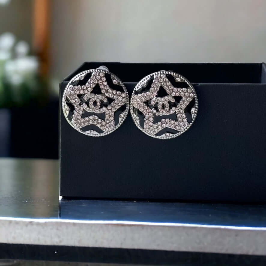 Chanel Round Silver & Black Double C with a Star Pattern Post EarringsBe daring and bold with these Chanel Round Silver & Black Double C Post Earrings. With a striking star pattern and sparkling crystals, these earrings will surely turn heads and make a s