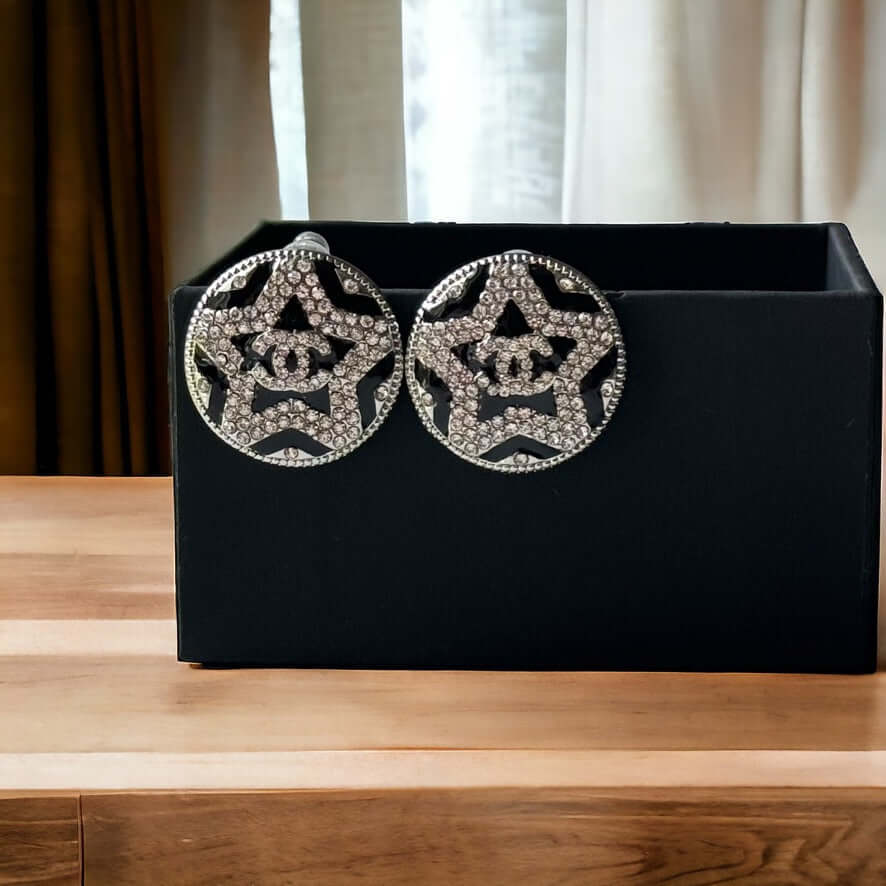 Chanel Round Silver & Black Double C with a Star Pattern Post EarringsBe daring and bold with these Chanel Round Silver & Black Double C Post Earrings. With a striking star pattern and sparkling crystals, these earrings will surely turn heads and make a s