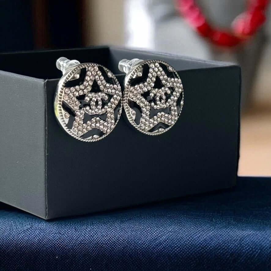 Chanel Round Silver & Black Double C with a Star Pattern Post EarringsBe daring and bold with these Chanel Round Silver & Black Double C Post Earrings. With a striking star pattern and sparkling crystals, these earrings will surely turn heads and make a s