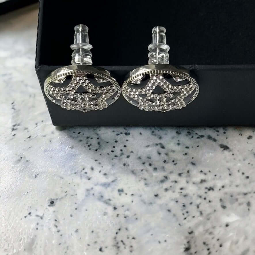 Chanel Round Silver & Black Double C with a Star Pattern Post EarringsBe daring and bold with these Chanel Round Silver & Black Double C Post Earrings. With a striking star pattern and sparkling crystals, these earrings will surely turn heads and make a s
