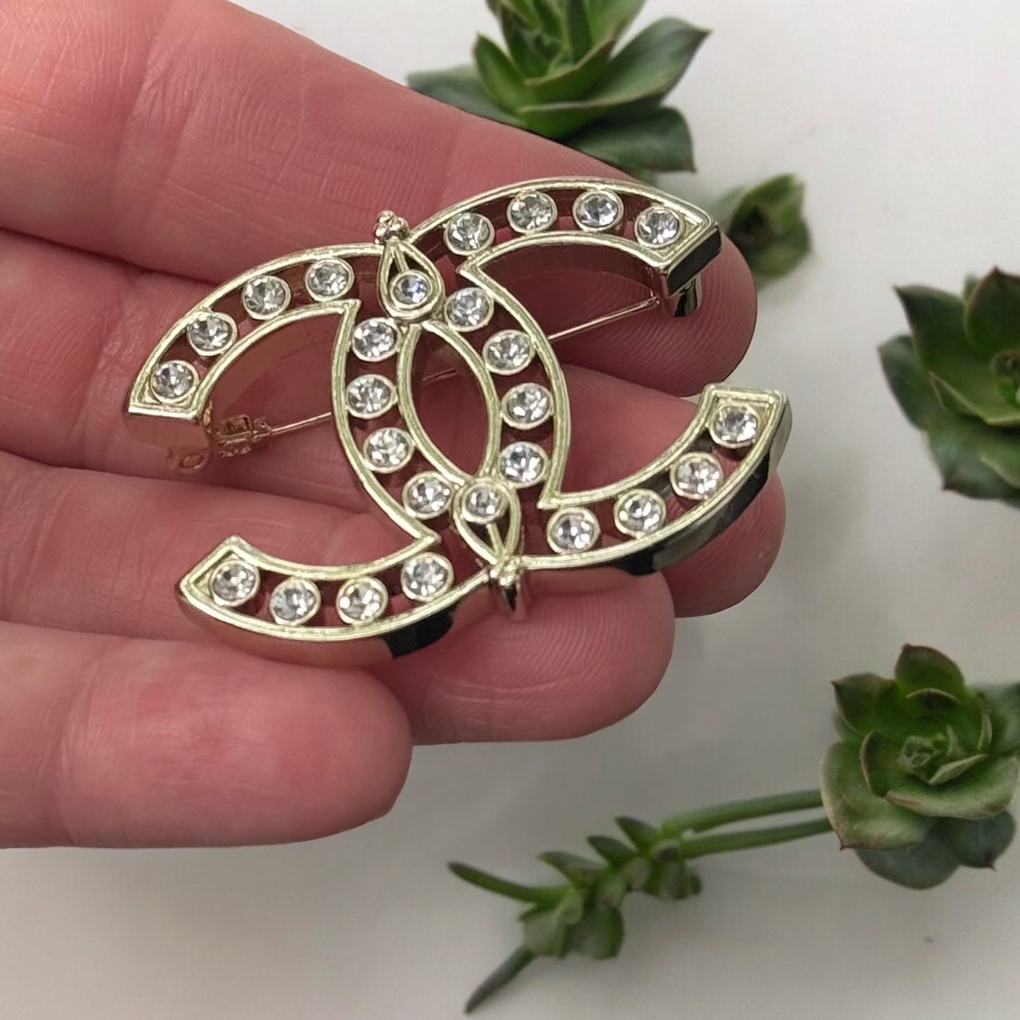 Chanel Strass Double C Cut Out with Clear Crystals Brooch Pin B23 ATransform any outfit into a statement piece with the Chanel Gold Double C brooch. Made in Italy, this brooch features bright clear crystals in Coco Chanel's signature cut-out design. Perfe