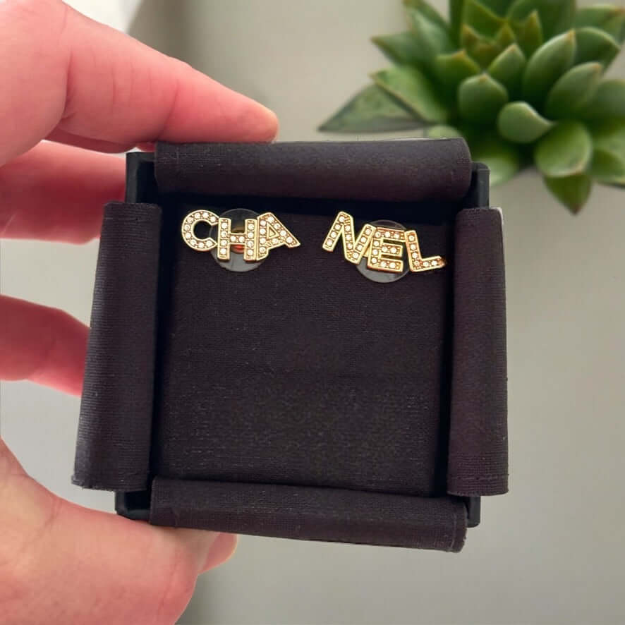 Chanel 14K Gold Name Cut-Out w/ clear crystals earringsAdd a touch of elegance and playfulness to your outfit with these Chanel 14K Gold Cut-Out Name earrings. The clear crystals add a subtle sparkle, making them perfect for any occasion. Their smaller si