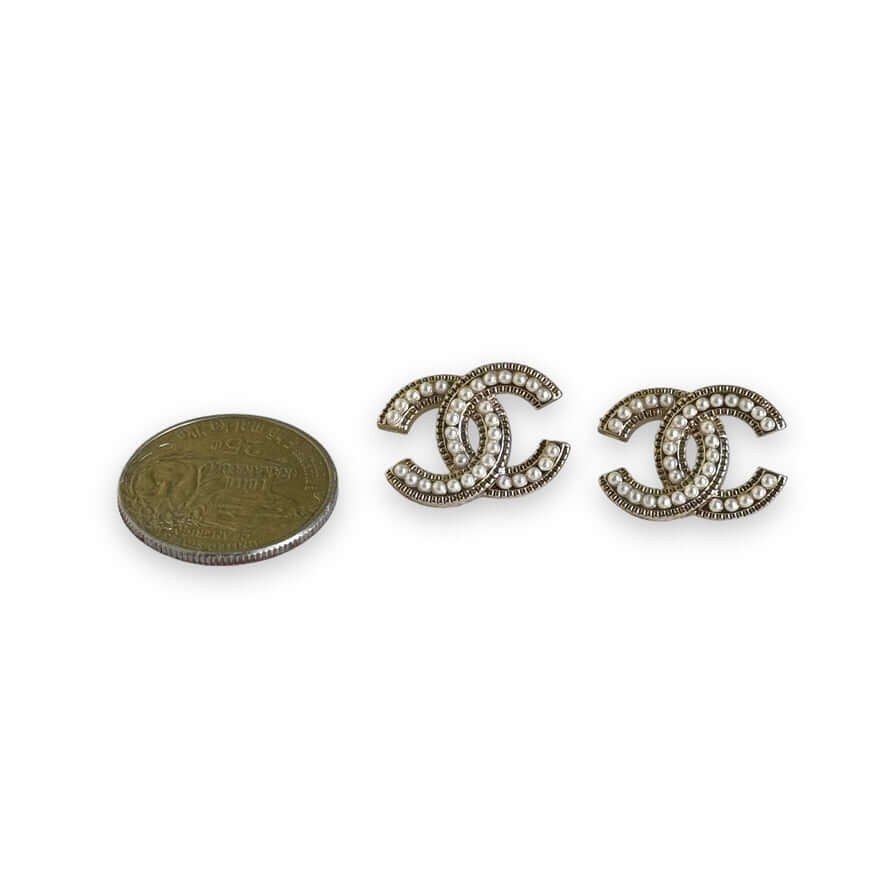 Chanel CC lighter gold tone post earrings encrusted with faux pearls next to coin for size comparison