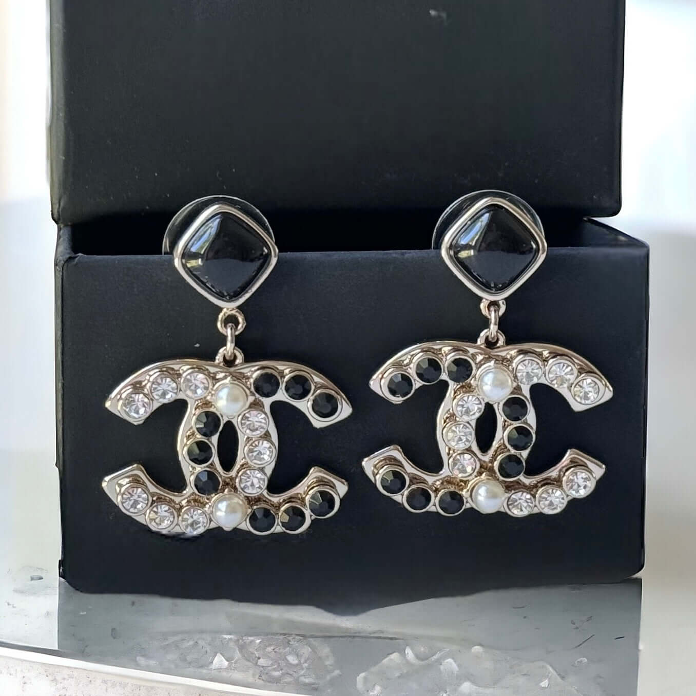 Chanel Gold Setting Double C Dangle Post EarringsAdd a touch of glamour to your outfit with these gold Chanel earrings featuring a double C design. The dangle style, adorned with faux pearls, clear crystals, and black stones, will catch everyone's eye wit