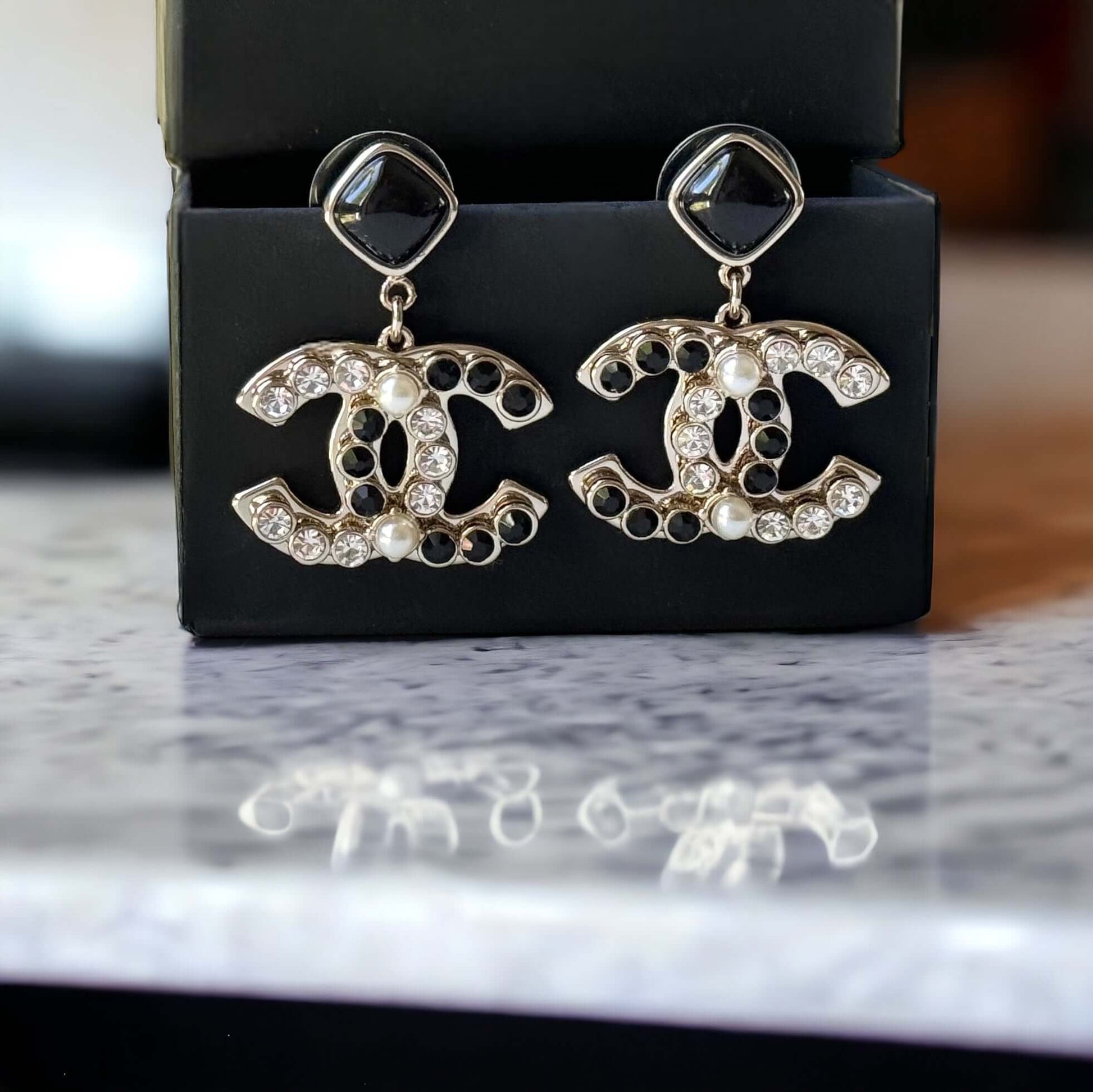 Chanel Gold Setting Double C Dangle Post EarringsAdd a touch of glamour to your outfit with these gold Chanel earrings featuring a double C design. The dangle style, adorned with faux pearls, clear crystals, and black stones, will catch everyone's eye wit