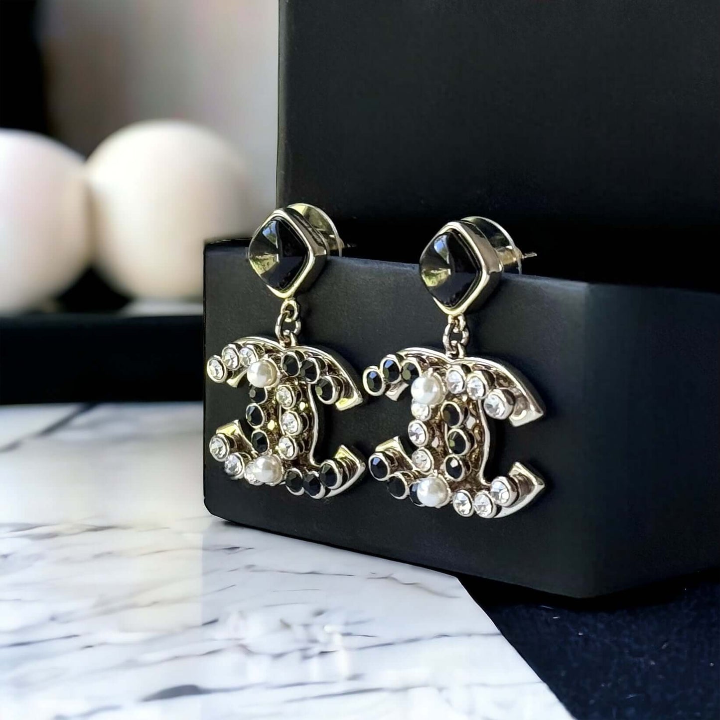 Chanel Gold Setting Double C Dangle Post EarringsAdd a touch of glamour to your outfit with these gold Chanel earrings featuring a double C design. The dangle style, adorned with faux pearls, clear crystals, and black stones, will catch everyone's eye wit