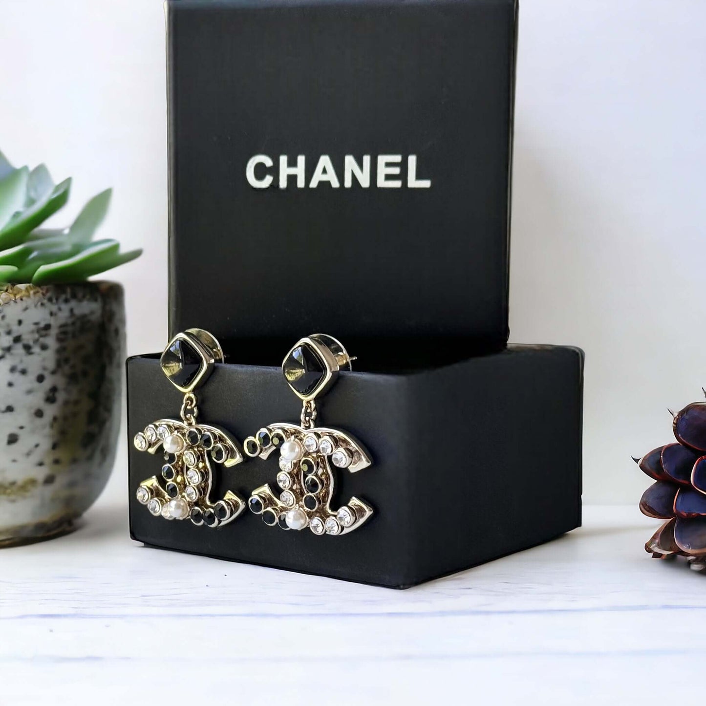 Chanel Gold Setting Double C Dangle Post EarringsAdd a touch of glamour to your outfit with these gold Chanel earrings featuring a double C design. The dangle style, adorned with faux pearls, clear crystals, and black stones, will catch everyone's eye wit