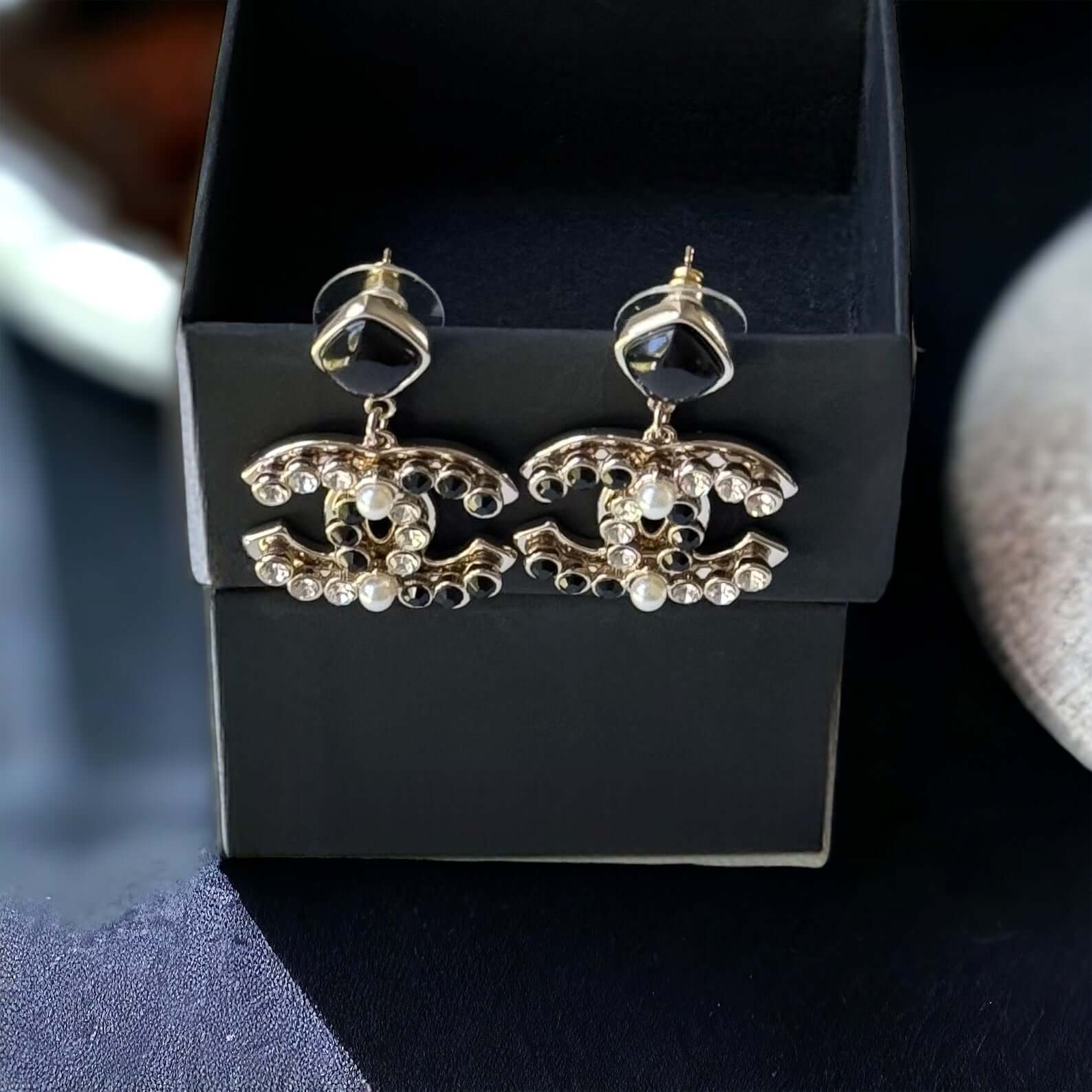 Chanel Gold Setting Double C Dangle Post EarringsAdd a touch of glamour to your outfit with these gold Chanel earrings featuring a double C design. The dangle style, adorned with faux pearls, clear crystals, and black stones, will catch everyone's eye wit