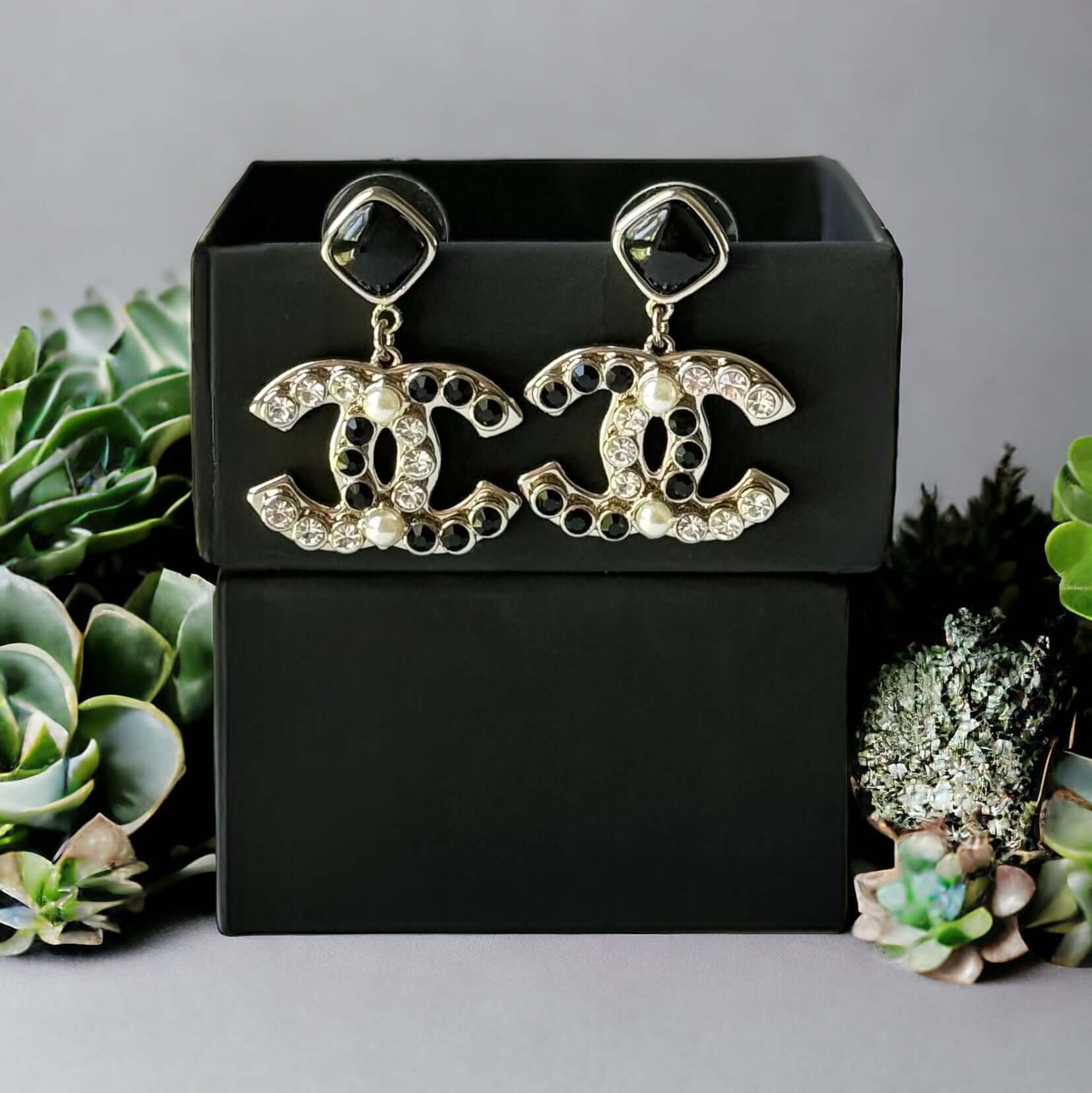 Chanel Gold Setting Double C Dangle Post EarringsAdd a touch of glamour to your outfit with these gold Chanel earrings featuring a double C design. The dangle style, adorned with faux pearls, clear crystals, and black stones, will catch everyone's eye wit