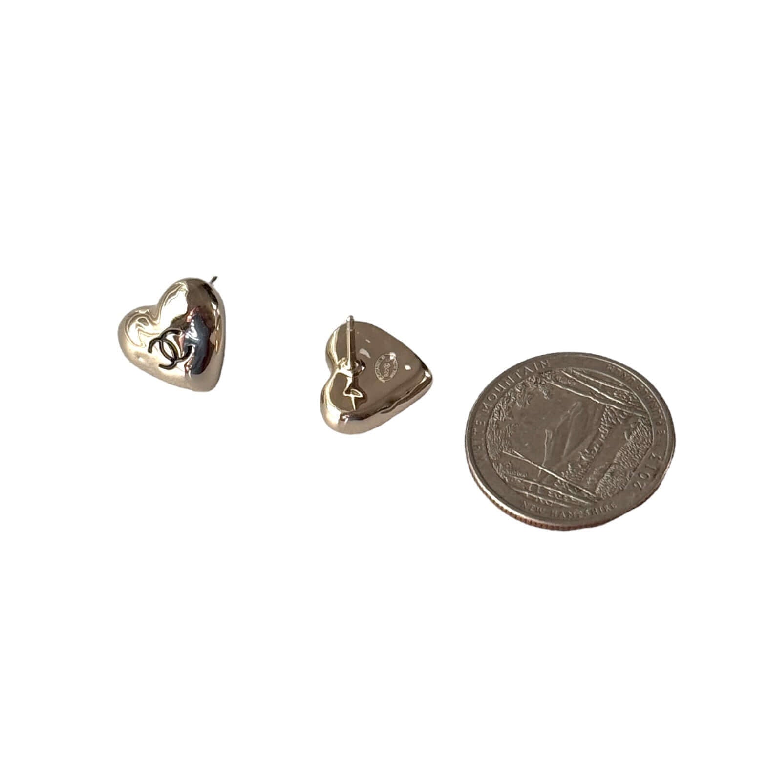 Authentic CHANEL gold plated puffy heart earrings with black enamel CC, alongside a quarter for size reference.