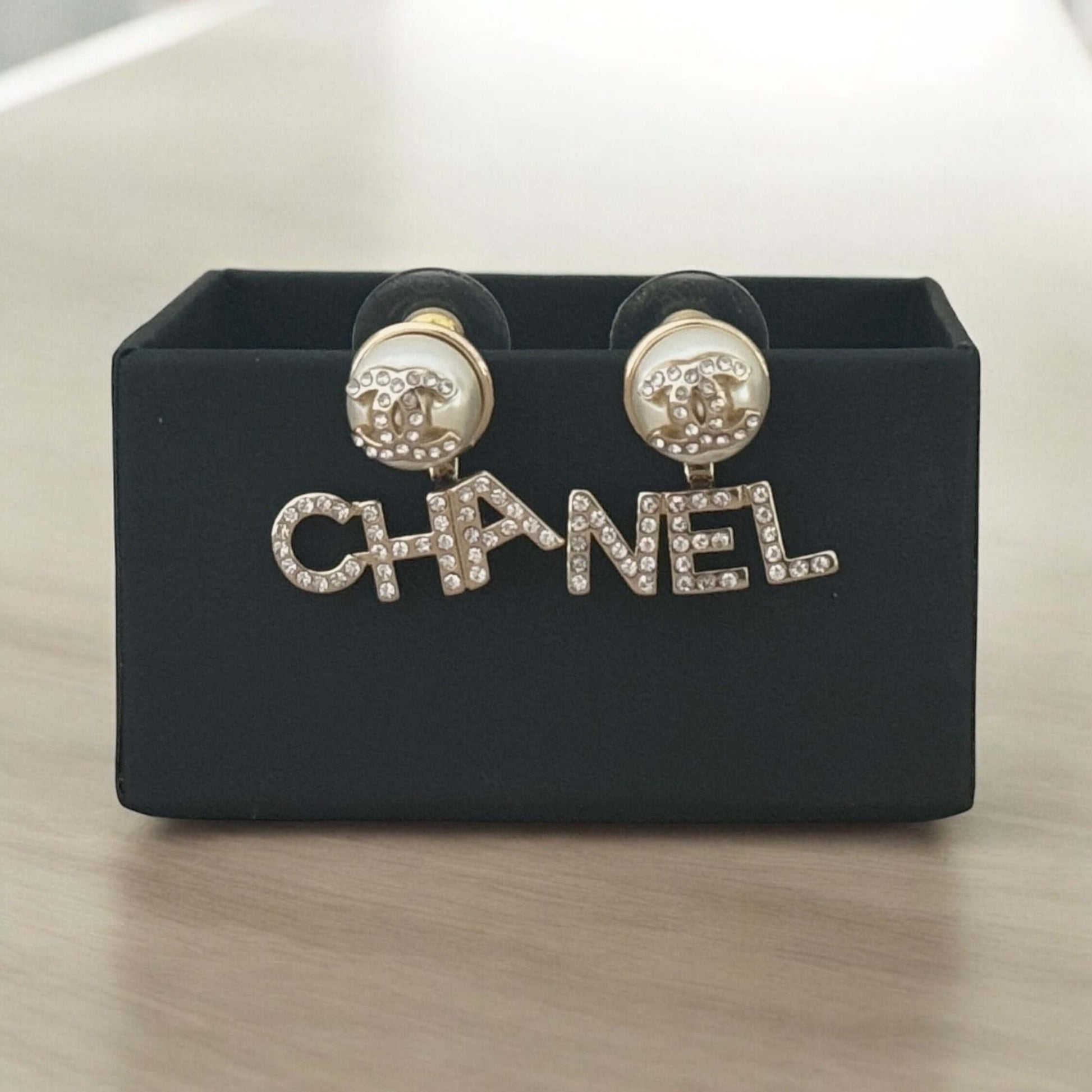 Chanel Gold CC Crystals Enamel Drop Earrings with clear crystals and pearlish off-white enamel displayed in original Chanel box.