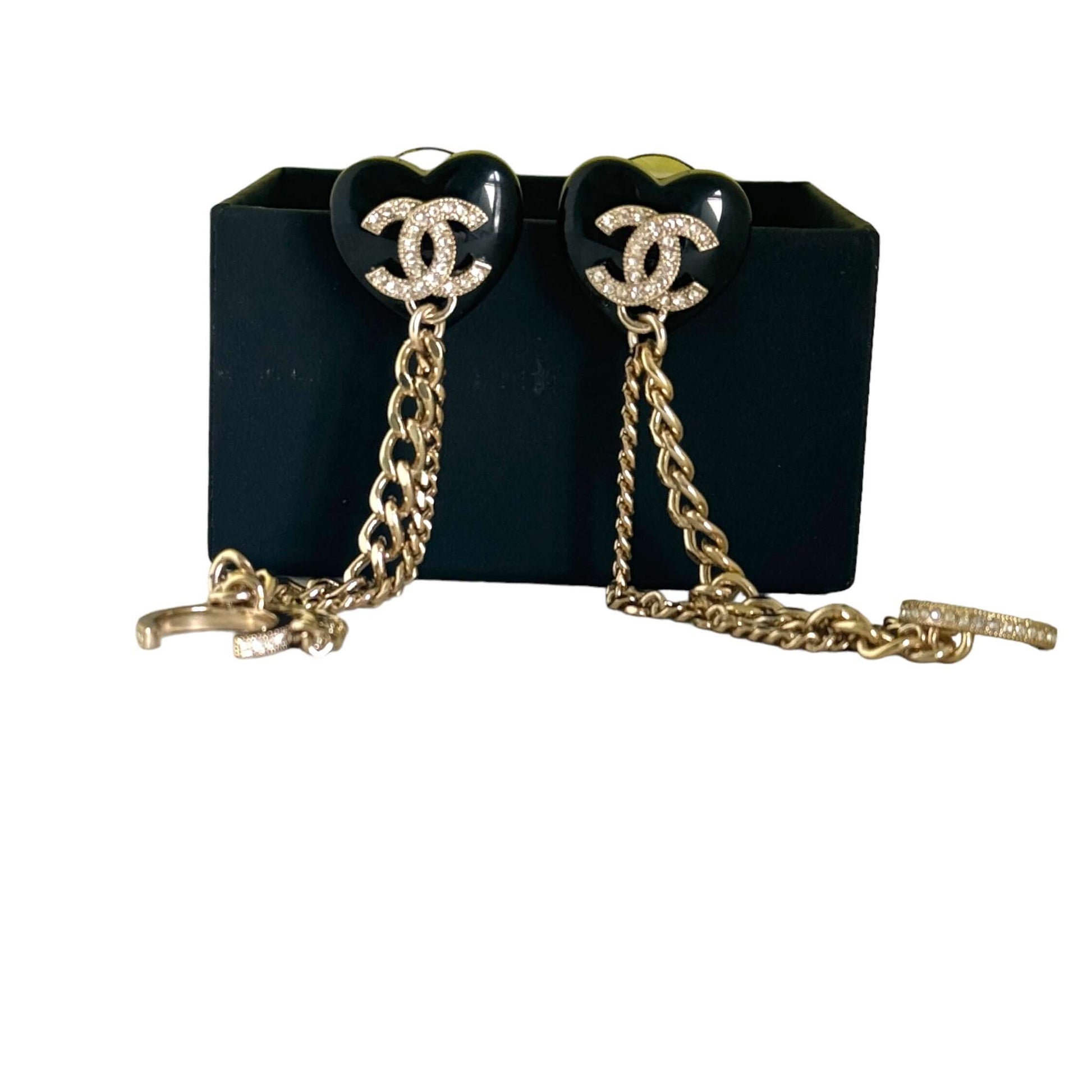 Chanel CC Gold & Black Chain Heart Earrings with Ear Cuff on display, featuring dangling gold chains and sparkling crystals on black lucite hearts.