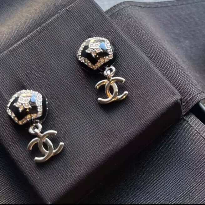 Chanel CC silver and black dangle earrings with star pattern and enamel, featuring mini CC dangle, displayed on black fabric