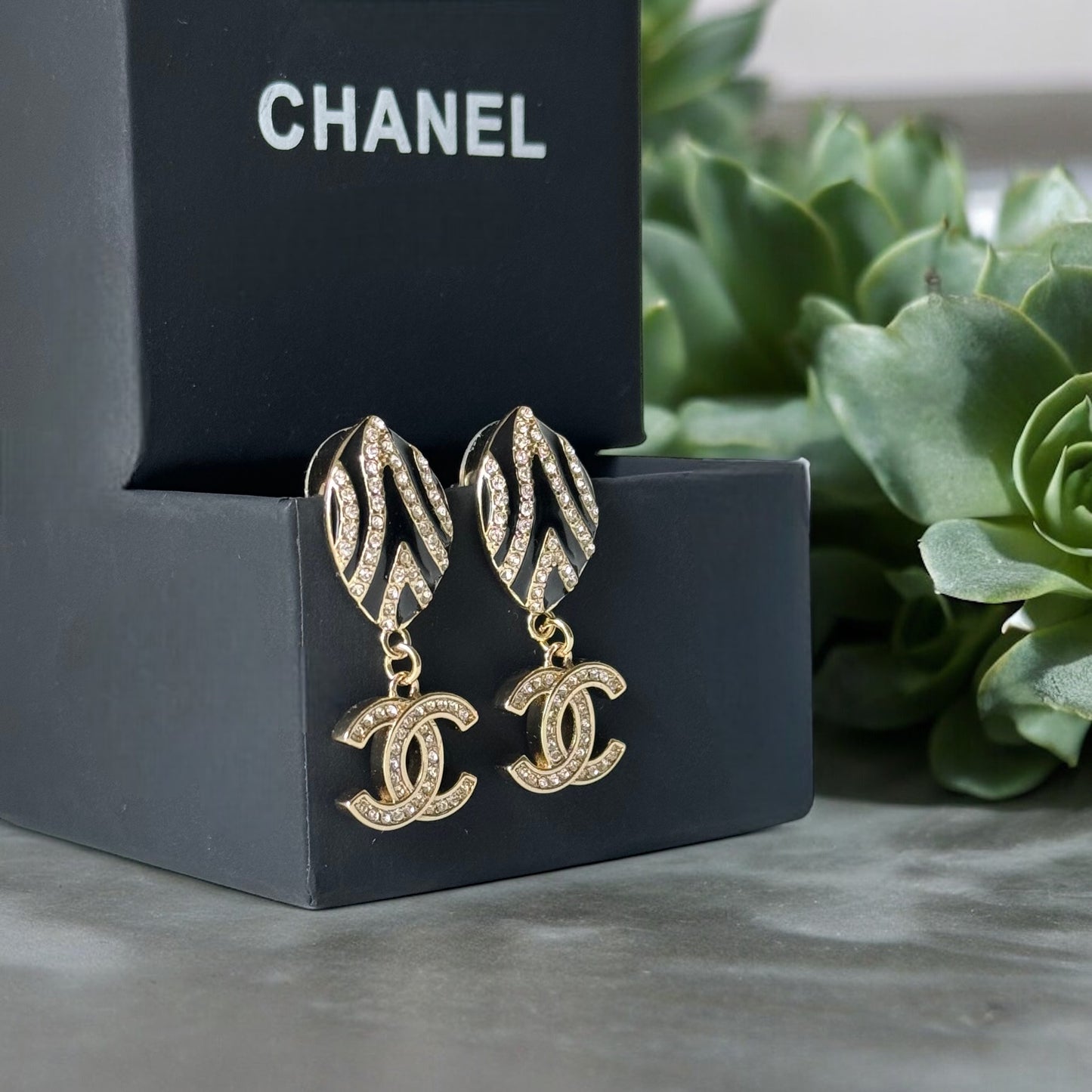 Chanel Gold Plated & Black Enamel & Crystals Oval Shaped Double C Dangling Post EarringsTake a bold step with these Chanel Gold Plated & Black Enamel & Crystals Oval Shaped Double C Dangling Post Earrings. The on-trend zebra-like design is perfect for ris