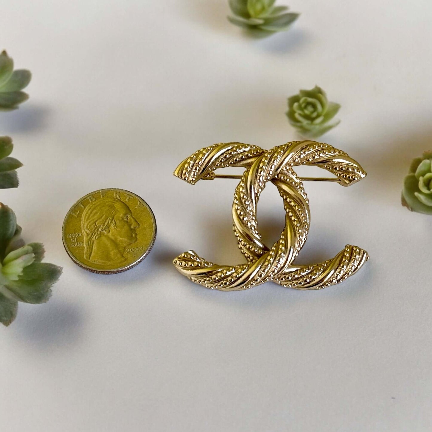 Add a touch of elegance and glamour to any outfit with the Chanel Gold Textured Twist CC Brooch Pin. Its twisted gold design and understated CC logo make it the perfect accessory for any occasion, all year round. Show off your sense of style with this mus