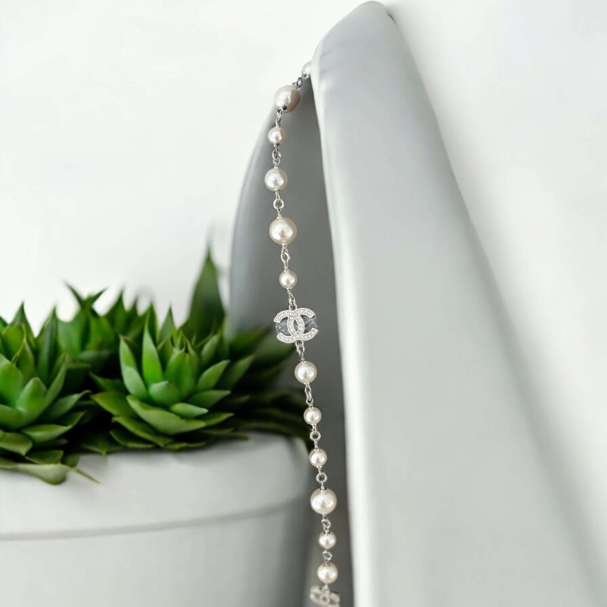 Authentic Chanel CC Pearl Wire Link Necklace 17 Pre-Owned displayed elegantly beside a potted plant.