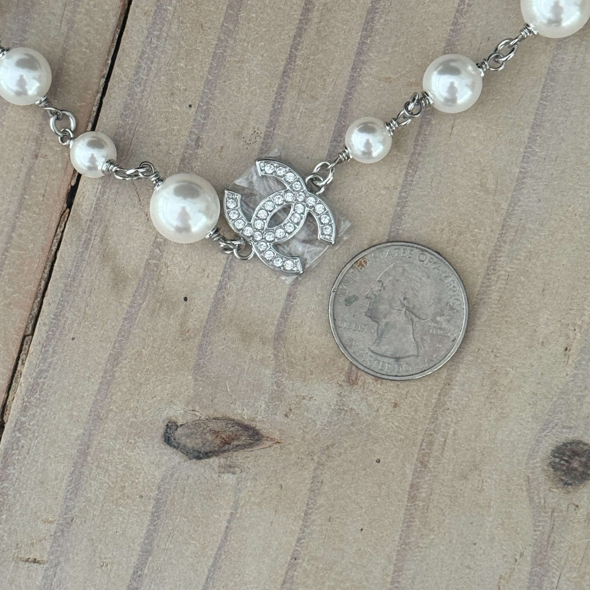 Authentic Chanel CC Pearl Wire Link Necklace 17 with a quarter for size comparison on wood background.