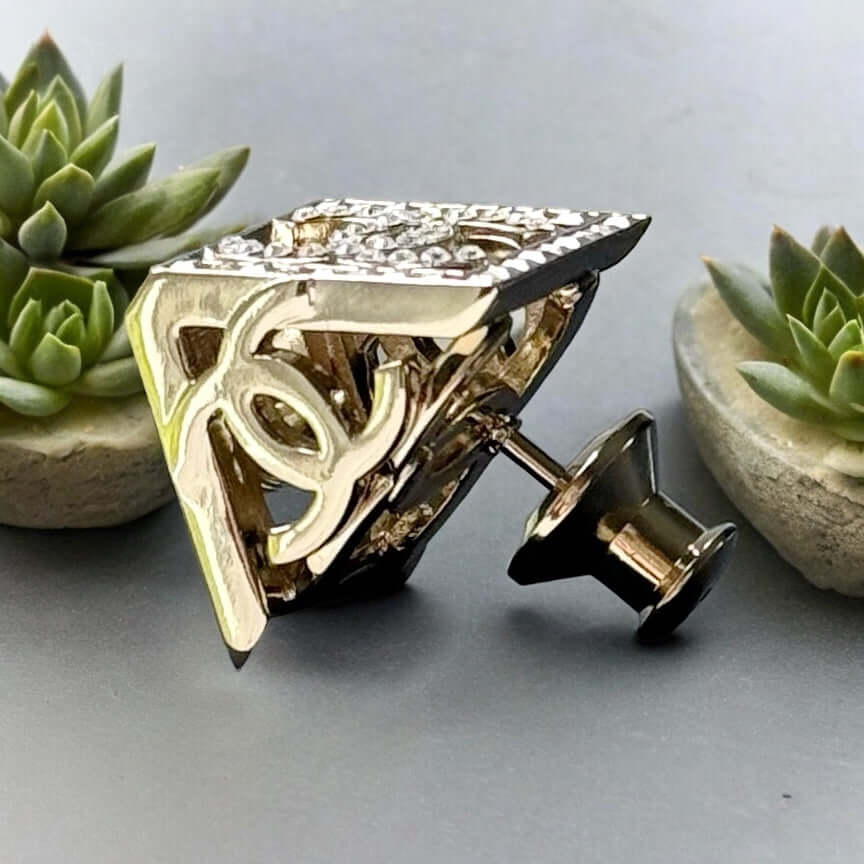 Chanel Lighter Gold Double C with Crystals Triangle Styled Smaller Brooch PinSet your style on fire with the Chanel Lighter Gold Double C brooch pin. Covered in dazzling crystals, this triangular piece adds a touch of bling to any outfit. Playfully chic,