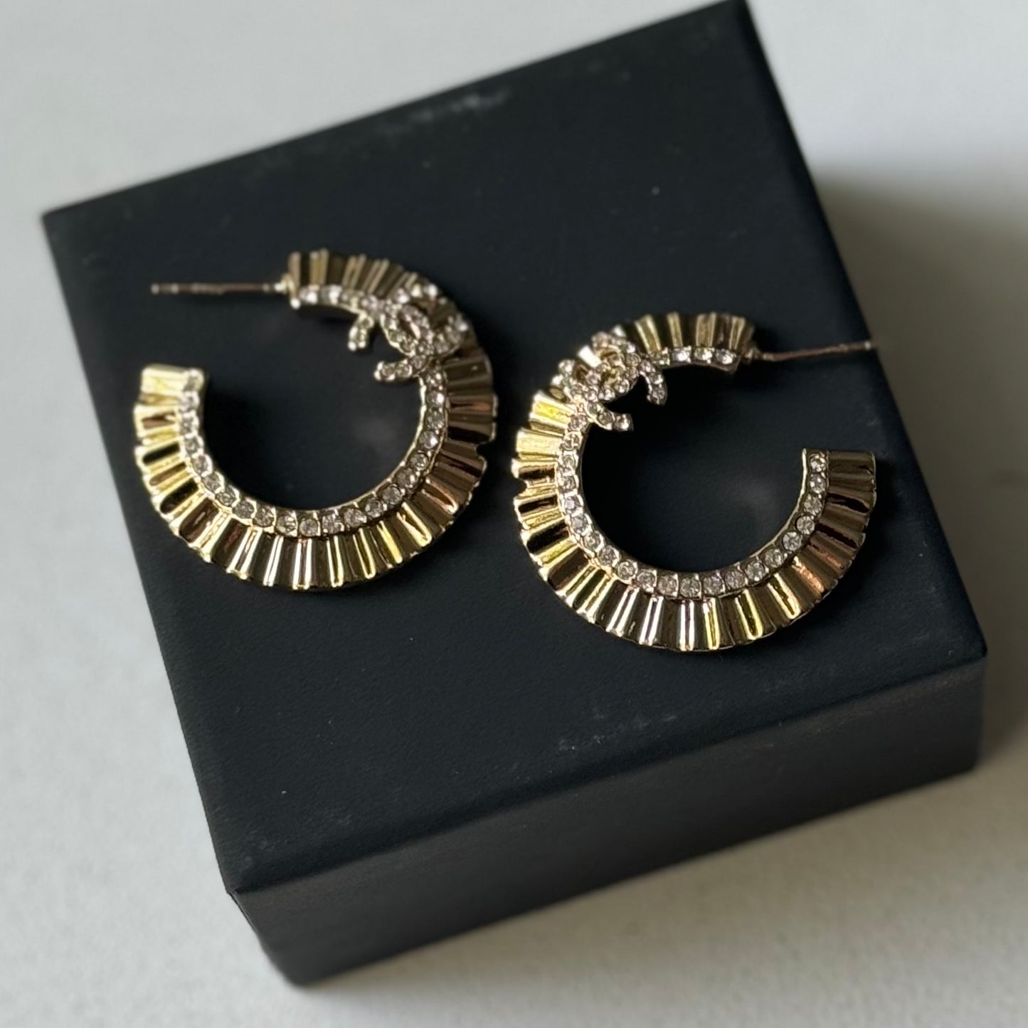 Gold Plated Chanel Flatten Hoops with Crystals Post EarringsStunning ! Gold Plated Bigger Hoops with great head turning texture with clear crystals accented along the inner side of these Double C Post Earrings Comes with the Chanel Box & Bag In clean grea