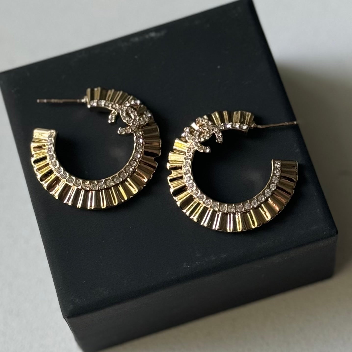 Gold Plated Chanel Flatten Hoops with Crystals Post EarringsStunning ! Gold Plated Bigger Hoops with great head turning texture with clear crystals accented along the inner side of these Double C Post Earrings Comes with the Chanel Box & Bag In clean grea